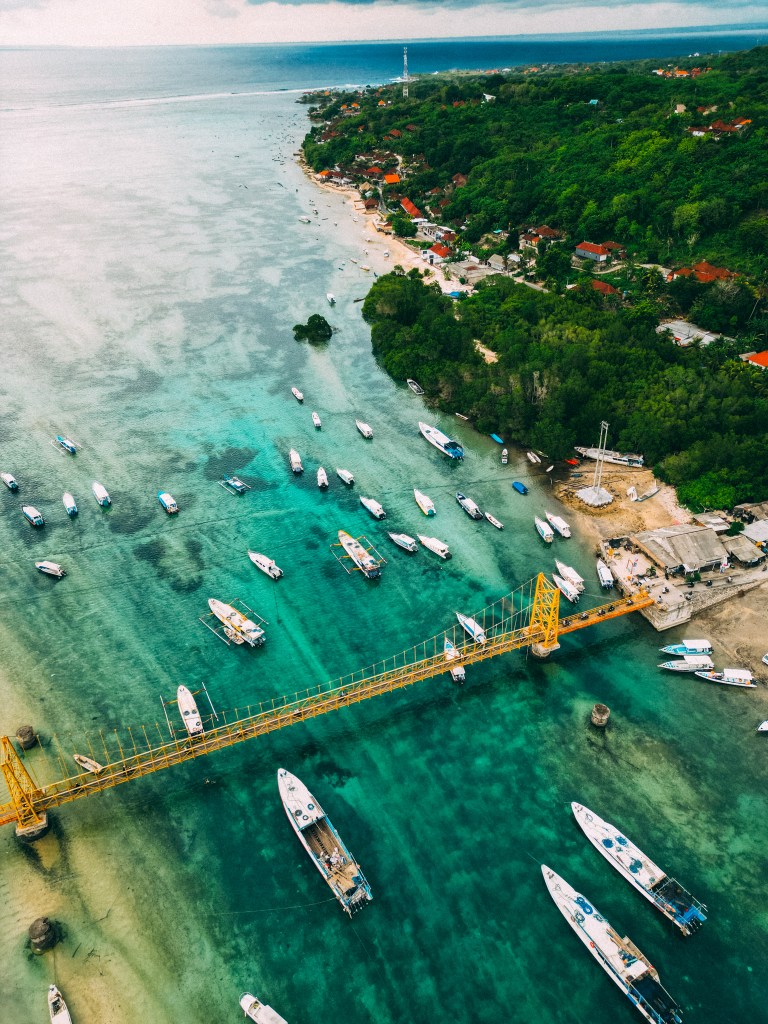 Aerial view of the Yellow Bridge linking Nusa Lembongan and Nusa Ceningan, with boats moored in the turquoise channel